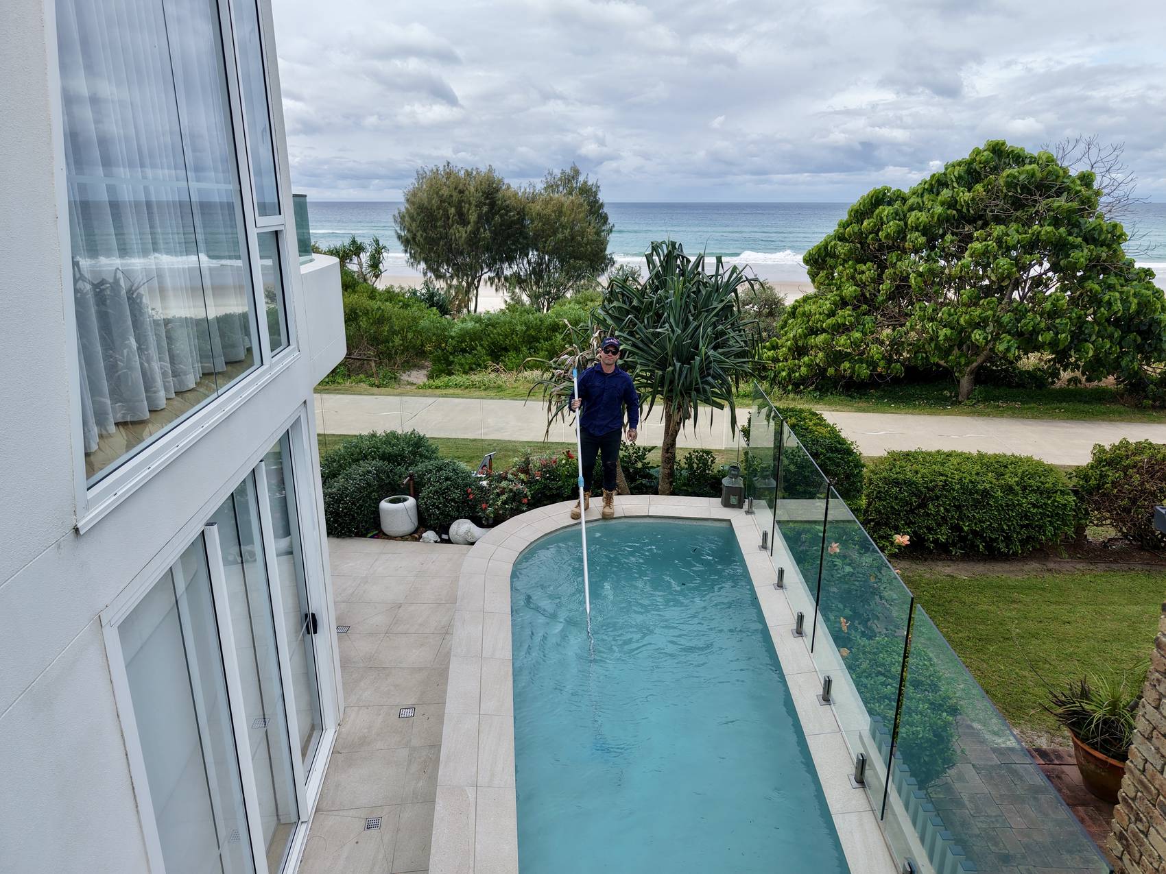 Blue Avenue Pools servicing a beachfront pool, ocean and beach visible behind